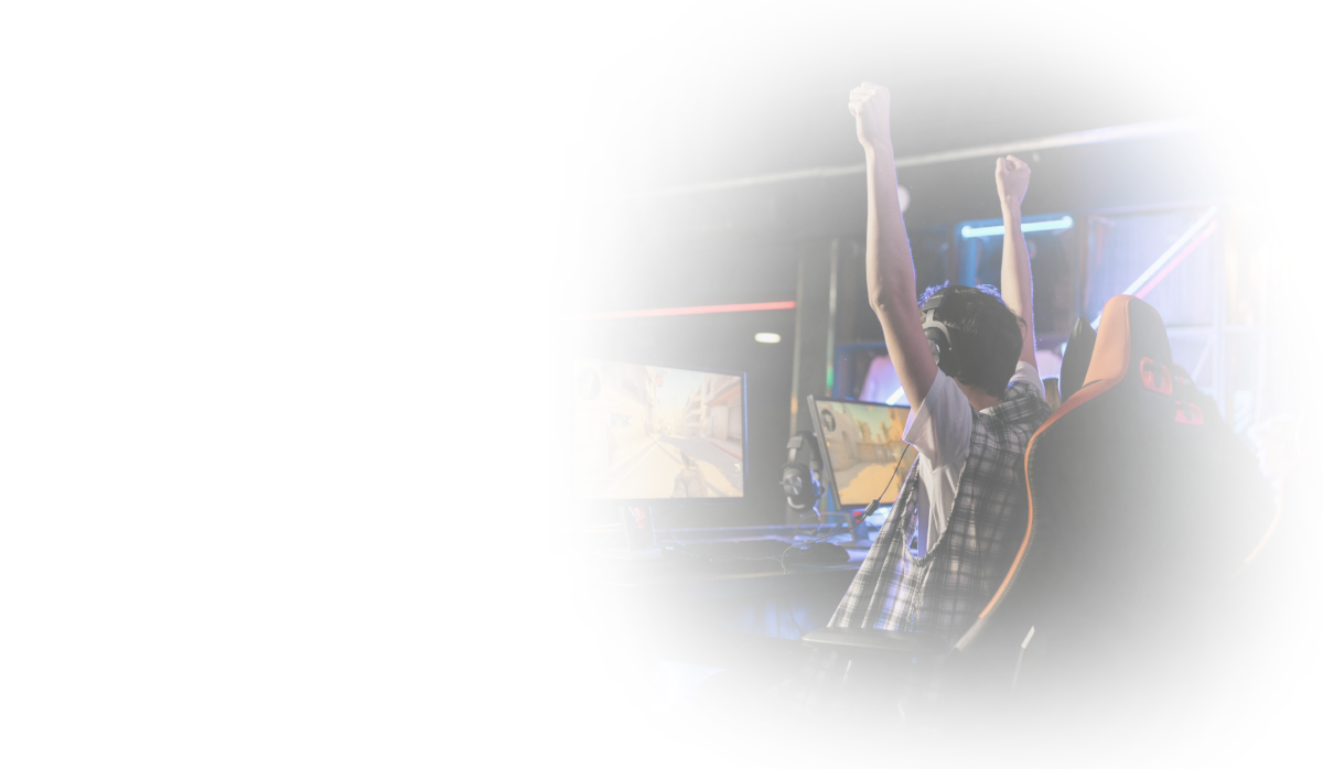 A man raises his hands in a gesture of victory, sitting in front of his computer.